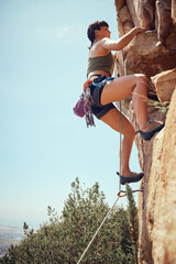 Mountain, climbing and sport with a sports woman or athlete abseiling outdoor for health and...