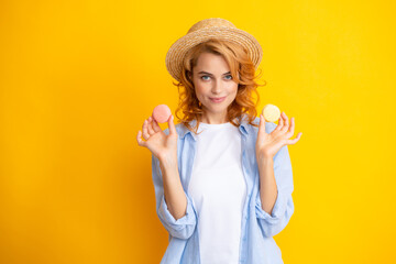 Woman eating a macaroon. Beautiful redhead woman in summer straw hat eating sweet macaroons. French dessert, sweets.