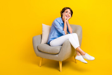 Fototapeta na wymiar Full length photo of pretty dreamy girl dressed blue shirt arms cheeks looking empty space isolated yellow color background