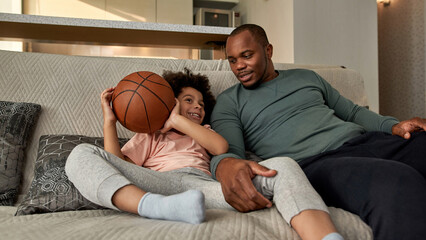 Black son and father watching basketball broadcast