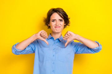 Closeup photo of young woman wear blue office shirt unhappy grimace bad mood thumbs down dissaproval employer isolated on yellow color background © deagreez