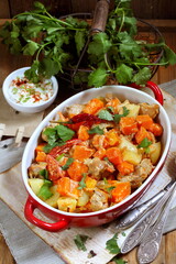Pumpkin with meat and vegetables in a ceramic form on a wooden table