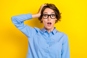 Closeup photo of young funny impressed shocked woman wear blue formal office shirt eyewear open mouth confused isolated on yellow color background