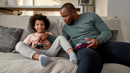 Father pushing joystick of son during video game
