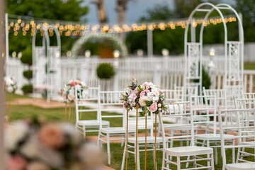 View of chairs, flowers, and wedding decoration objects in a garden in the evening