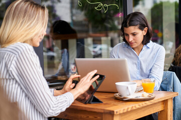 Medium-shot of two female diverse co-workers focused on their work in outdoors office