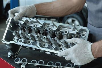 Car parts. The cylinder head of the internal combustion engine. An auto mechanic installs hydraulic...