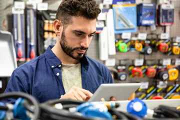 Male hardware shop owner taking inventory on digital tablet