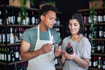 Liquor store coworkers holding bottle and glass of wine