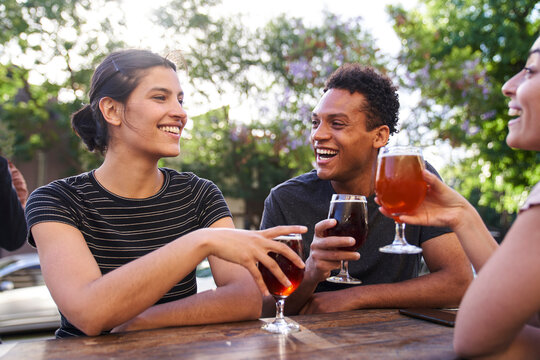 Mid-shot of young Latin-American woman and her diverse group of friends enjoying craft beer
