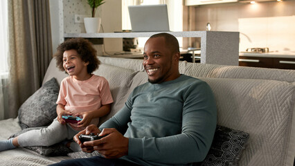 Little boy and father playing video game on sofa © Svitlana