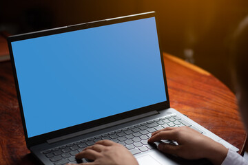 A women hands are typing keyboard playing laptop with blue empty screen on the table, graphic orange light, technology and internet connection concept. copy space for individual text and design