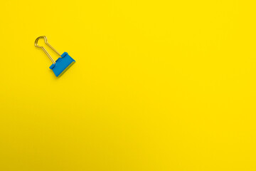 Binding clips in blue color for paper on yellow background