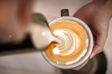 Top view of barista making a cup of vegan soya coffee latte art