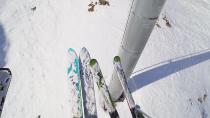 Riding oon a chair lift. View of all mountain and slalom skis.