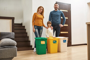Young family near dustbins for different trash