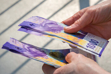 hands holding a stack of swiss francs money