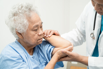 Obraz premium Asian senior or elderly old lady woman patient feel pain her elbow on bed in nursing hospital ward, healthy strong medical concept.