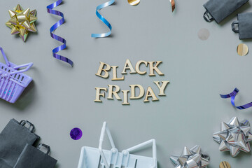 Black friday text with gifts, shopping baskets and festive tinsel flat lay