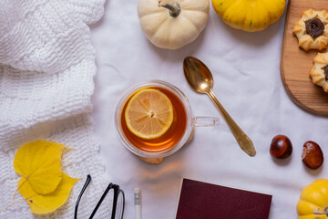Cup of tea and autumn cozy decor with sweater and pumpkins top view