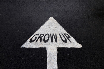 White traffic arrow on rainy road with letters Grow up concept. Business growth direction.