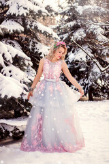 Obraz na płótnie Canvas Beautiful woman in a luxurious blue fairy-tale dress in a snowy forest