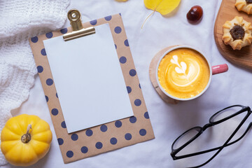 Blank sheet of paper and latte cup with autumn cozy decor top view. Copy space for autumn text