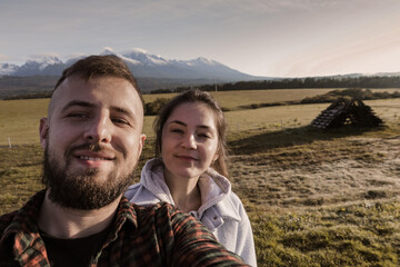 The couple takes a souvenir photo with a view of the mountains. A guy and a girl are taking a selfie. Tatra Mountains.