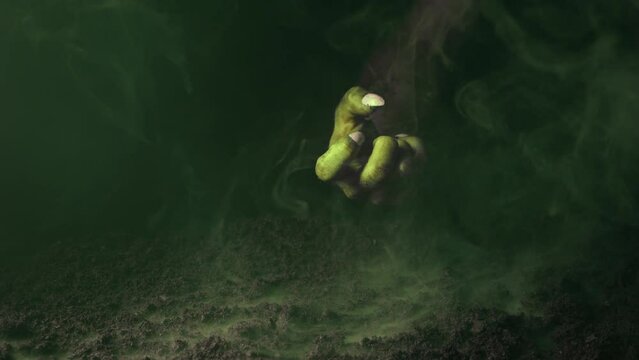 A terrible hand with claws emerges from the fumes of smoke over the graveyard ground.