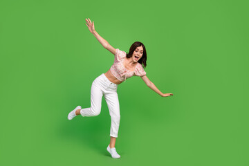 Fototapeta na wymiar Full size photo of lovely positive woman with wavy hairstyle dressed white pants blouse look down fall isolated on green color background
