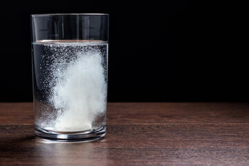 Effervescent tablet in a glass of water close-up on a black background. The concept of health.