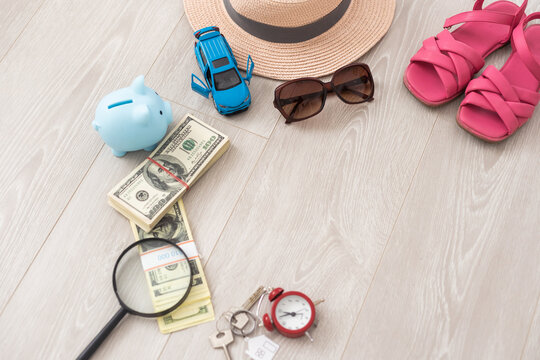 A piggy bank with dollar bills in a travel setting. In the composition of the image: Sun Hat, Alarm Clock. Concept of saving money for traveling on vacation.