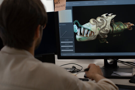 Caucasian male artist designer draws by stylus on tablet 3D models for games in office
