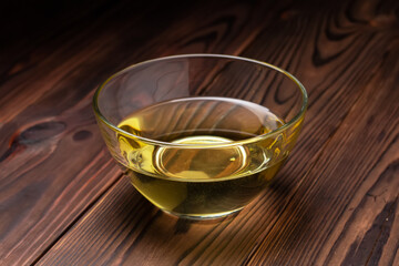Sunflower oil in glass bowl on wooden boards.