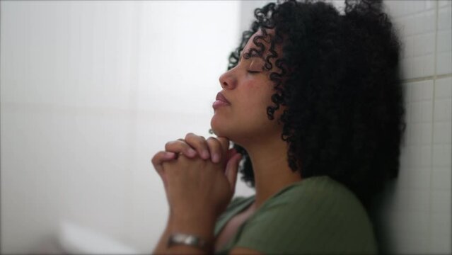 One Brazilian young woman in prayer during difficult times. A South American black latina adult girl seeking help and support. Hope and Faith concept