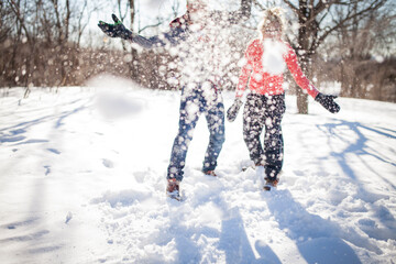 Couple throwing snowball at the camera in park.