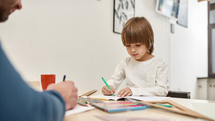 Little boy and cropped man drawing pens at table