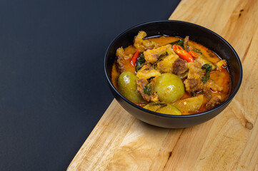 Top view of Curry with Beef Recipe in a black bowl (Panang Neua), Thai food Beef peanut-coconut cream curry, Thai curry red soup,Thailand tradition red curry with beef.