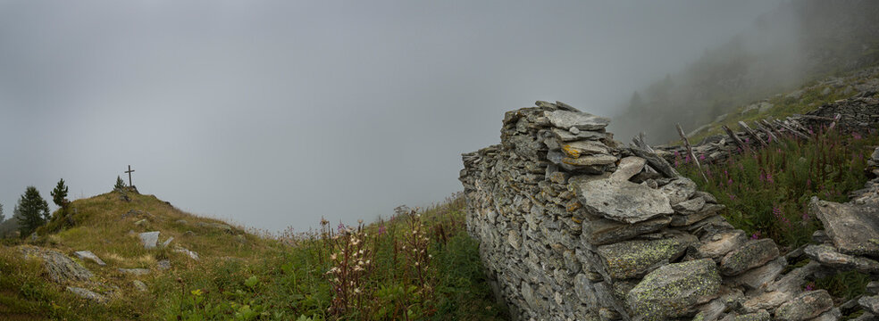 A mountain shrine by the path in the Alpine region near Mont Blanc, a cross near Fenetre D'Arpette, low clouds and mist.