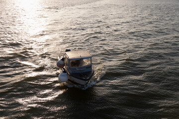 A small fishing boat on the sea at sunset, elevated view.
