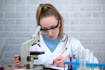 The laboratory assistant writes down the results of the experiments in a notebook. School...