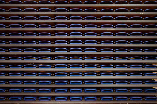 A row of folded seats on shelves in an indoor sports venue.