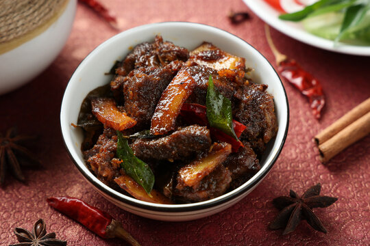 Spicy red beef fry curry and brown rice South Indian dish Kerala, India. side of Ghee rice, Appam, Parotta, Puttu. traditional Christian Muslim feast dish. Buffalo roast, meat pepper fry with coconut.