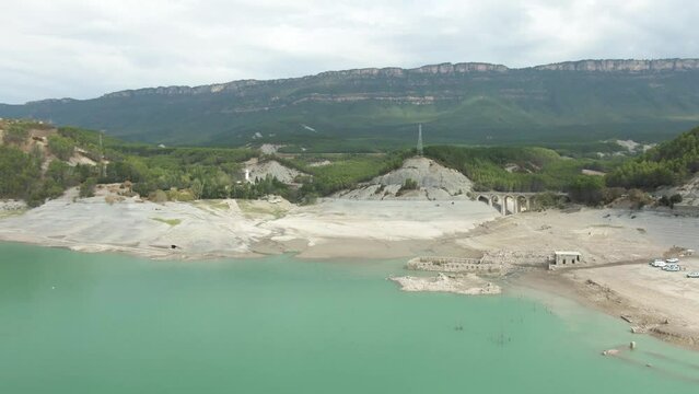 Aerial view of the ruins of the Tiermas spa resurfaced from the water by the drought in the reservoir of Yesa. Camera move dolly in.