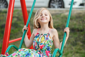 Child girl rides on swing at playground. Childhood, entertainment and leisure concept.