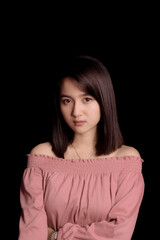 Young Asian woman wearing a pink crop top. Stand and take half body on black background. Express emotions.