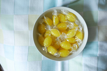 Yellow candy in white bowl on tablecloth