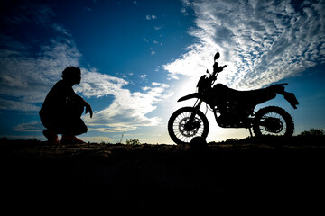 Obraz na płótnie Canvas Silhouette Man enjoying a motocross bike on a beautiful evening in the mountains.