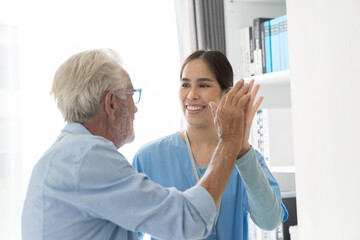 Obraz premium Female nurse physical therapy elderly man at hospital ward. Asian female nurse caring elderly man patient. Hospital care and older adults concept