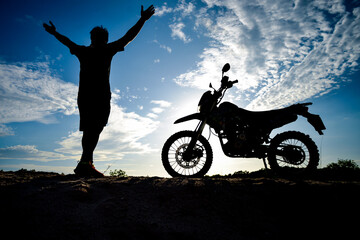 Fototapeta na wymiar Silhouette Man enjoying a motocross bike on a beautiful evening in the mountains.